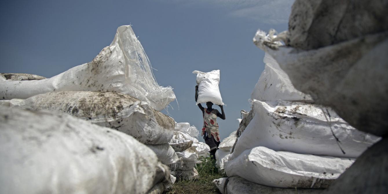 A woman carries a sack of food airdropped by WFP and distributed by Oxfam in Jonglei.