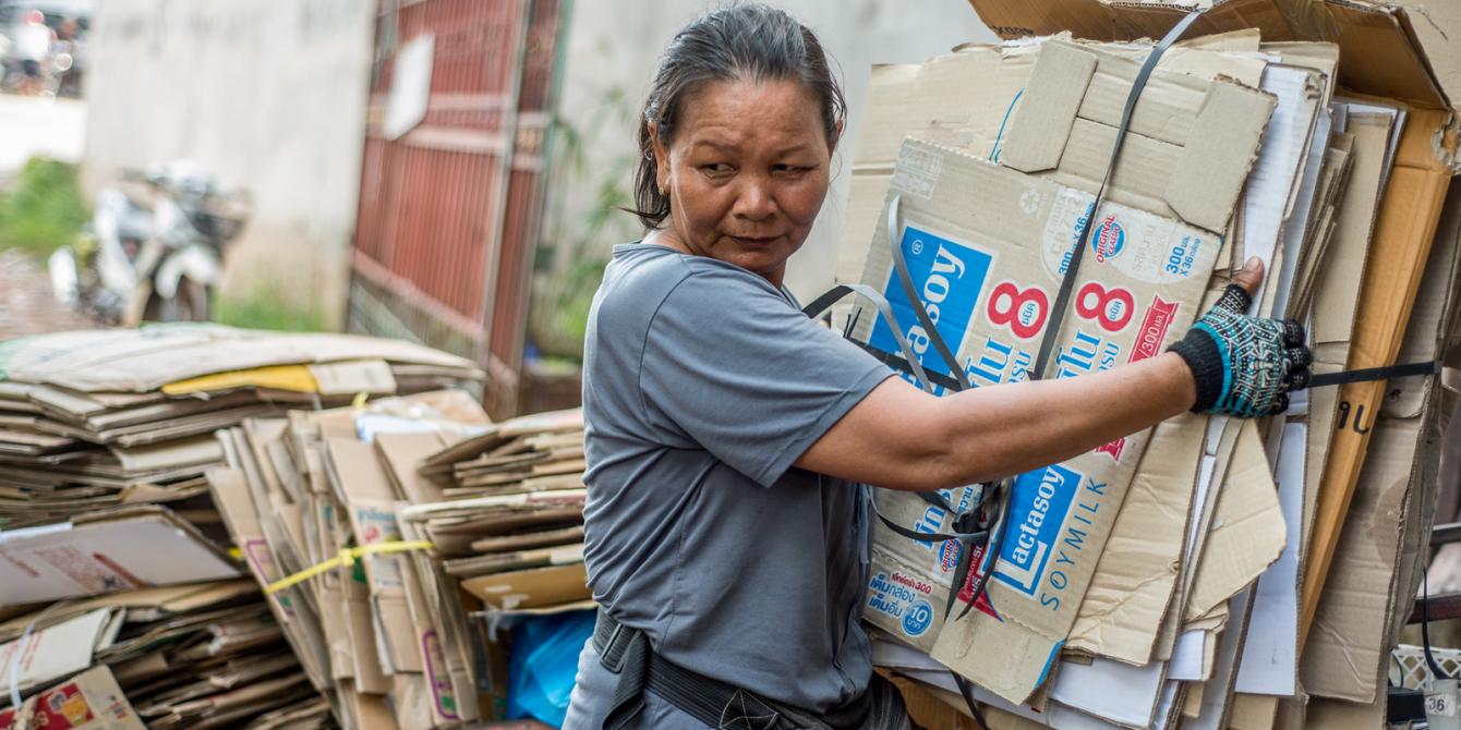 Lao Informal Workers A Lao female informal worker carries a stack of old cardboard boxes for recycling