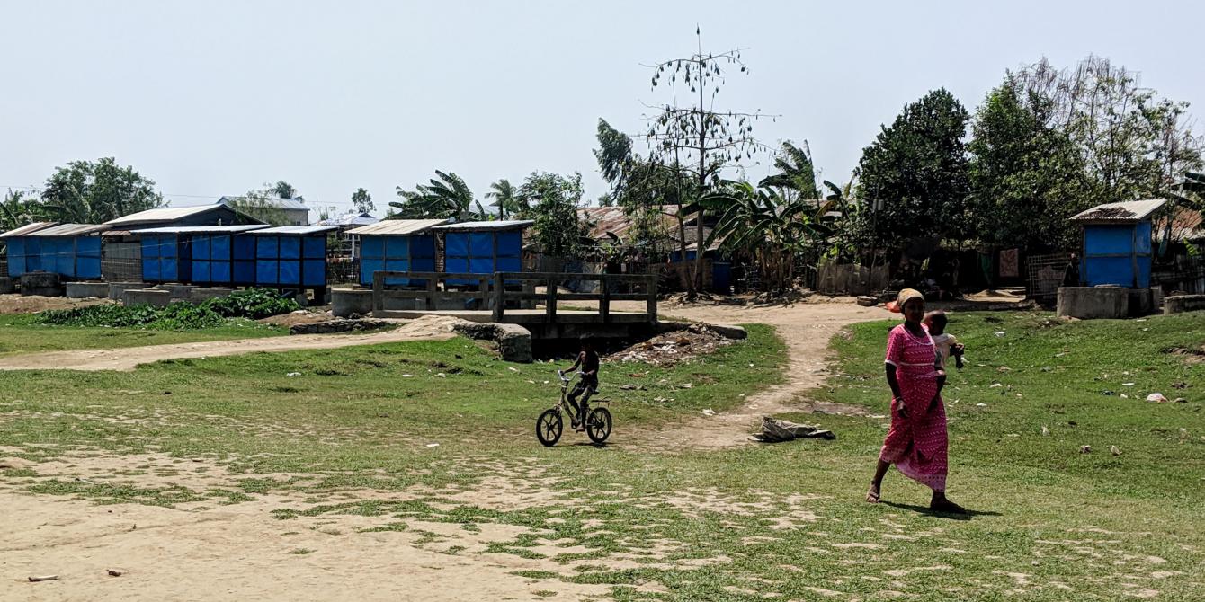 Women and children in the camps walk past latrines built by Oxfam and SolidaritesInternational