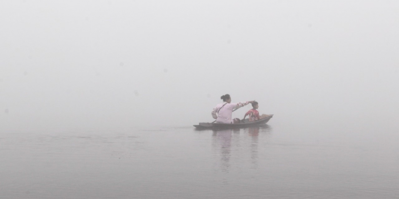 A boat carrying woman and child in the river.