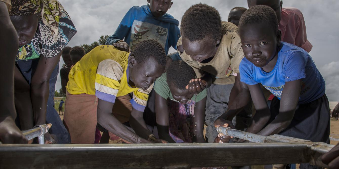 Young South Sudanese refugee boys playing and taking water at of the Oxfam setup tap stands in Adjumani district photo credit: Julius Kasujja/Oxfam young south Sudanese refugee boys taking water at an Oxfam setup tap stand. credit: Julius Kasujja/Oxfam